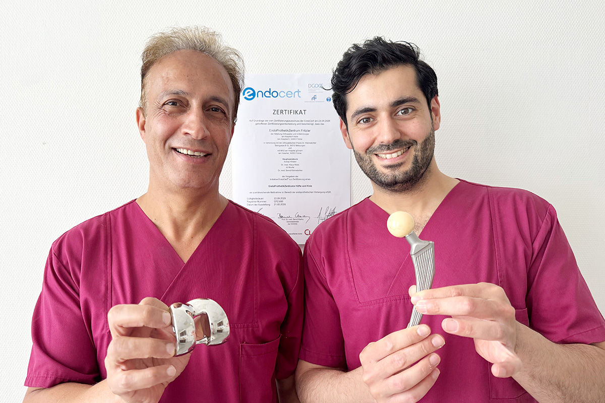 Die beiden Ärzte Herr Noufal und Herr Subayi stehen nebeneinander und halten eine Hüftprothese in der Hand